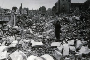 Une normande traverse les décombres de la rue Pont-Mortain à Lisieux après les bombardements de juin 1944. Photo : DR