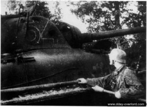 7 juin 1944 : un soldat allemand inspecte la carcasse d'un char Sherman anglais abandonné. Photo : Bundesarchiv