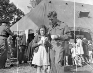 20 août 1944 : le soldat A. Sicotte aux côtés de Chislaine LaFeure lors d'une journée des enfants organisée au quartier général de la 1ère armée canadienne à Amblie. Photo : Archives Canada