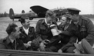 On an airfield in Normandy, near a Lancaster bomber, a crew of the Royal Air Force tries the smell of Norman cheeses. Photo: IWM