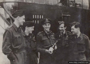 The crew of the "Q for Queenie", 297th Squadron, opening their first bottle of liberation in front of the Lancaster bomber. From left to right: Brian Easton, Vic Clements, Roy Shortman, George Jenkins and Jim Peppit. Photo: IWM