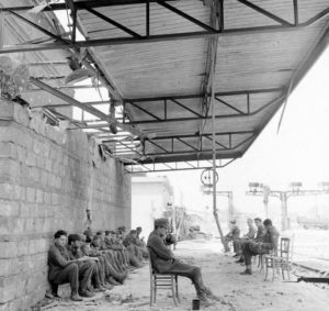 Des prisonniers allemands appartenant à la 272. Infanterie Division sont gardés par des soldats canadiens dans les vestiges de la gare de Caen en juillet 1944. Photo : Library and Archives Canada