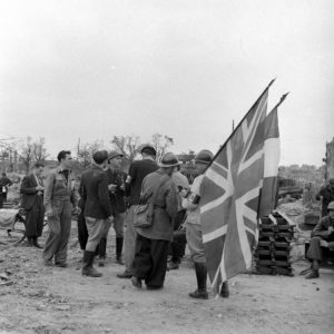 Devant le pont Bailey baptisé "Churchill bridge" à Caen (construit le 20 juillet 1944), des résistants français appartenant à la compagnie Scamaroni. Ils portent les drapeaux français et britannique notamment pour éviter un tir fratricide de la part des Alliés. Photo : George Rodger pour LIFE Magazine