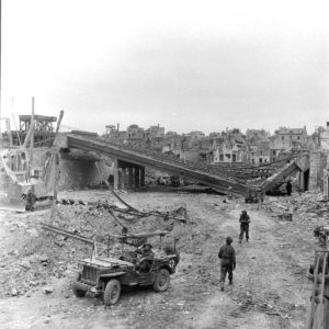 Les vestiges du pont ferroviaire saboté par les Allemands à Caen, rue de la gare, en juillet 1944. Une Jeep médicalisée et un bulldozer Caterpillar blindé D7A sont visibles. Photo : George Rodger pour LIFE Magazine