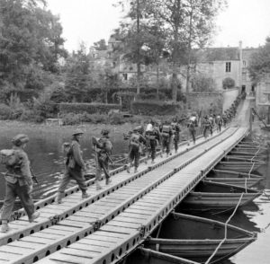 Le 19 juillet 1944 à Caen, à hauteur de l'actuelle rue de l'Arquette, des fantassins lourdement équipés traversent l'Orne sur un pont de bateaux. Photo : DR