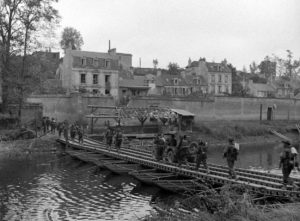 Le 19 juillet 1944 à Caen, à hauteur de l'actuelle rue de l'Arquette, des fantassins lourdement équipés et une Jeep traversent l'Orne sur un pont de bateaux. Photo : DR