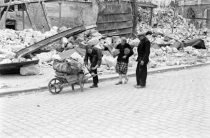 Juillet 1944 : au pied de l'église Saint-Pierre de Caen, des civils normands déplaçant probablement les maigres vestiges précieux de leur maison dans une brouette. Photo : George Rodger pour LIFE Magazine
