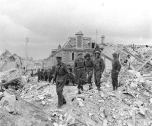 Dans les décombres de la rue d'Haleine (devenue l'Esplanade de la Paix) à Caen en juillet 1944, le Lieutenant General John T. Crocker, commandant le 1st Corps, inspecte les lieux. Photo : George Rodger pour LIFE Magazine