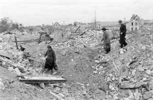 Juillet 1944 à Caen : des civils normands avancent dans les décombres des ruines, dans les quartiers nord de la ville. Photo : George Rodger pour LIFE Magazine