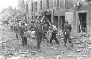 Juillet 1944 : des résistants français appartenant à la compagnie Scamaroni dans les ruines de Caen, rue d'Auge. Ils portent les drapeaux français et britannique notamment pour éviter un tir fratricide de la part des Alliés. Photo : George Rodger pour LIFE Magazine