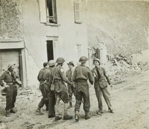 9 juillet 1944 : des soldats alliés appartenant aux Civils Affaires entrent dans la ville de Caen. Le préfet Pierre Daure (avec chapeau) et le commandant Léonard Gille (avec une cigarette) se portent à leur rencontre. Photo : Library and Archives Canada