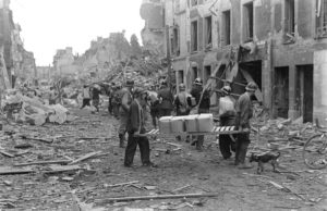 Juillet 1944 : des résistants français appartenant à la compagnie Scamaroni dans les ruines de Caen, rue d'Auge. Ils portent les drapeaux français et britannique notamment pour éviter un tir fratricide de la part des Alliés. Photo : George Rodger pour LIFE Magazine