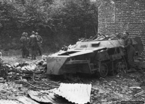 17 juin 1944 : l'épave d'un SdKfz 250 du Panzer Artillerie Abteilung de la Panzer-Lehr Division inspecté par des soldats anglais de la 49th Infantry Division dans Cristot. Photo : IWM