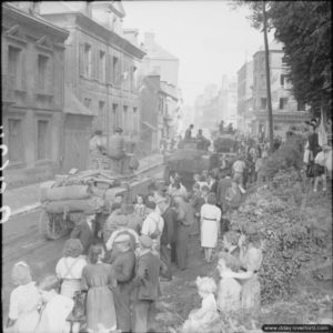 23 août 1944 : les habitants de Gacé se pressent le long des routes pour observer le passage de blindés Stuart alliés dans la ville (route de Lisieux, place du château). Photo : IWM