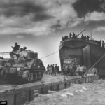 Débarquement depuis un LST sur un ponton face au secteur Jig Green de Gold Beach d'un char Sherman et de camions appartenant à la 56th Infantry Brigade, 50th Northumbrian Infantry Division. Photo : IWM