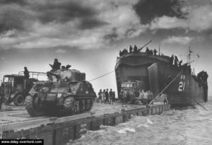 Débarquement depuis un LST sur un ponton face au secteur Jig Green de Gold Beach d'un char Sherman et de camions appartenant à la 56th Infantry Brigade, 50th Northumbrian Infantry Division. Photo : IWM