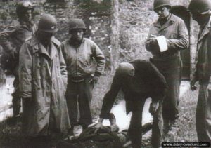 Ernest Moucel a enterré les 9 parachutistes américains massacrés par les Allemands dans le cimetière d’Hémevez. Il est présent lors de la levée des corps en compagnie d’officiers américains. Photo : US National Archives