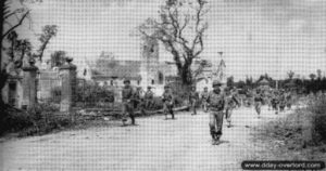 Colonnes de soldats américains devant les ruines de l’église de La Meauffe. Photo : US National Archives