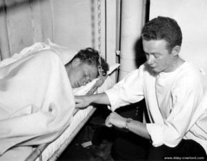 A doctor checks an injured man while crossing the Channel to England. Photo: US National Archives