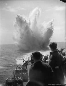 HMS Holmes drops an underwater charge off the coast of Normandy against the probable presence of a German submarine. Photo: IWM