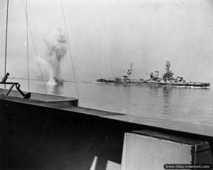 L'USS Texas sous le tir des batteries allemandes de la Festung Cherbourg le 25 juin 1944, vu depuis l'USS Arkansas. Photo : US National Archives