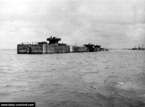 Mise en place des caissons Phoenix surmontés de tourelle pour canon antiaérien remorqué à travers la Manche. Photo : US National Archives