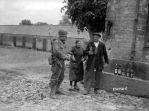 Des habitants de Colleville-sur-Mer partagent cidre et calva avec un soldat américain. Photo : US National Archives