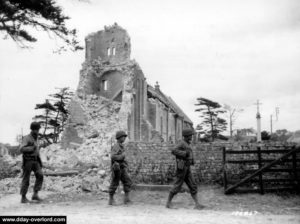 Patrouille devant l'église en ruine de Colleville-sur-Mer. Photo : US National Archives