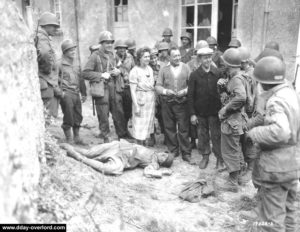 Des civils normands échangent avec des soldats américains à Colleville-sur-Mer autour du cadavre d'un soldat allemand. Photo : US National Archives