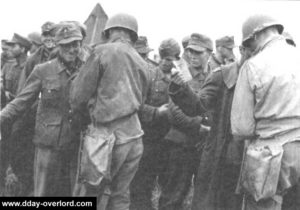 Fouille des prisonniers allemands à Omaha Beach avant leur déplacement vers les navires. Photo : US National Archives
