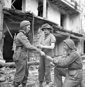 De gauche à droite : le Sapper Raymond Rheaume, le Corporal Gordon Cooper et le Sapper George McKinney du Royal Canadian Engineers (R.C.E.) préparent des charges explosives afin de déblayer des gravats et des bâtiment détruits rue de Bayeux à Caen, le 10 juillet 1944. Photo : Library and Archives Canada