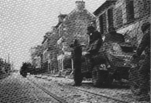 Le 11 juillet 1944, rue du général Moulin à Caen, un photographe de guerre échange avec l'équipage d'un véhicule blindé léger Humber appartenant à la 6th Field Company, Royal Canadien Engineer, 3rd (CA) Infantry Division. Un char M4 Sherman est visible en arrière-plan. Photo : Library and Archives Canada
