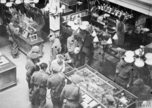 Dans Bayeux durant l'été 1944, des militaires britanniques achètent des souvenirs dans les boutiques de la commune. Photo : IWM A 24510