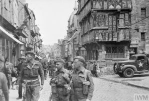 Dans Bayeux à l'été 1944, des militaires britanniques déambulent à l'angle de la rue Saint-Martin et la rue des Cuisiniers. Photo : IWM A24511
