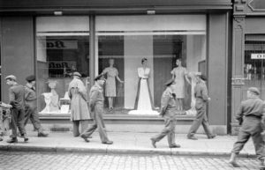 Des militaires britanniques et des civils devant une vitrine située au numéro 61 rue Saint-Malo à Bayeux, durant l'été 1944. Photo : LIFE Magazine