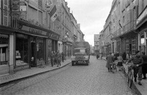 Des militaires britanniques et des civils dans la rue Saint-Malo à Bayeux durant l'été 1944. Un camion Austin K6 "Lorry" avance sur la route. Photo : LIFE Magazine