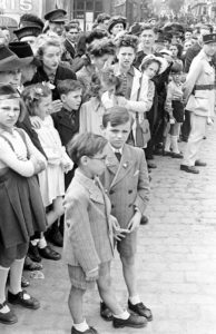 Des militaires britanniques, américains et français au milieu de la population normande assistent au défilé du 14 juillet 1944 à Bayeux, rue du maréchal Foch. Photo : George Rodger pour LIFE Magazine