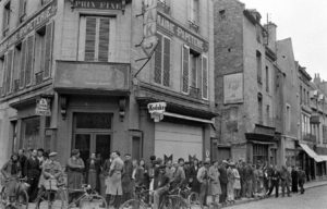 Des habitants observent le passage des troupes alliées à l'angle de la rue Saint-Malo et de la rue Genas Duhomme à Bayeux durant l'été 1944. Photo : LIFE Magazine