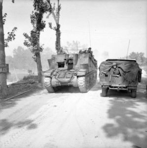 Canon automoteur M7 Sexton appartenant au 5th Regiment Royal Horse Artillery de la 7th Armoured Division quittant le pont "Euston 2" à Ranville en direction d'Escoville le 18 juilet 1944. Le camion vu de l'arrière est un Morris CS8. Photo : IWM B 7565