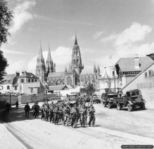 27 juin 1944 : des troupes traversent la ville de Bayeux. La cathédrale Notre-Dame de Bayeux est visible en arrière-plan. Photo : IWM