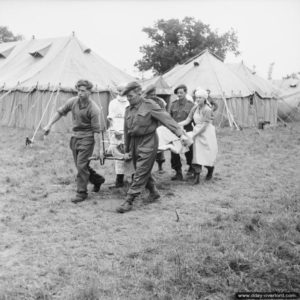 20 juin 1944 : des éléments du R.A. Medical Corps du Queen Alexandra’s Imperial Military Nursing Service prennent en compte un blessé au No 79 General Hospital. Photo : IWM