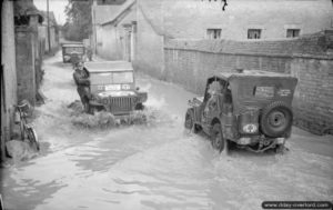 21 juillet 1944 : des Jeep traversent une rue inondée de Bretteville-l’Orgueilleuse. Photo : IWM