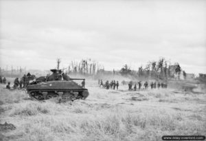 9 juillet 1944 : un char Sherman et de l’infanterie progressent dans le secteur de Buron en direction de Caen dans le cadre de l’opération Charnwood. Photo : IWM