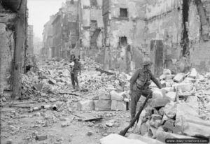 10 juillet 1944 : un soldat anglais porte une petite fille à travers les ruines de la ville de Caen. Photo : IWM