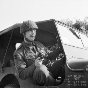 24 juillet 1944 : le Sergeant Norman Midgley, photographe à la No. 5 Section of the Army Film and Photographic Unit, dans une Jeep pendant la bataille de Caen. Photo : IWM