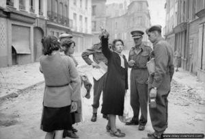 Le lieutenant general J. T. Crocker, commandant le 1er corps, discute avec des habitants de Caen. Photo : IWM