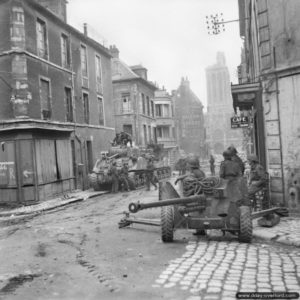 Une pièce antichar britannique défend les accès au centre-ville de Caen, rue des Chanoines, à proximité de deux chars Sherman. Photo : IWM