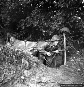 3 juillet 1944 : le sapeur Joe Laci de la 6th Field Company, Royal Canadian Engineers, sort de son trou de combat, sa Sten prête à tirer. Photo : IWM