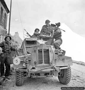 11 juillet 1944 : le lieutenant George Cooper, membre de la Canadian Army Film and Photo Unit, discute avec son beau-frère le Captain R. T. Miller, à bord d’un véhicule de reconnaissance Humber. Photo : IWM