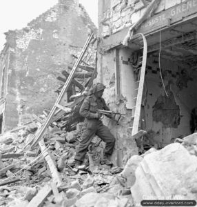 10 juillet 1944 : un soldat du Stormont, Dundas and Glengarry Highlanders armé d’un pistolet-mitrailleur allemand MP40 dans les ruines de Caen. Photo : IWM